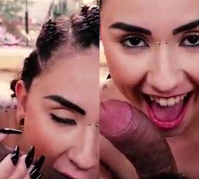 Mujer sonriendo y chupando las bolas de un hombre